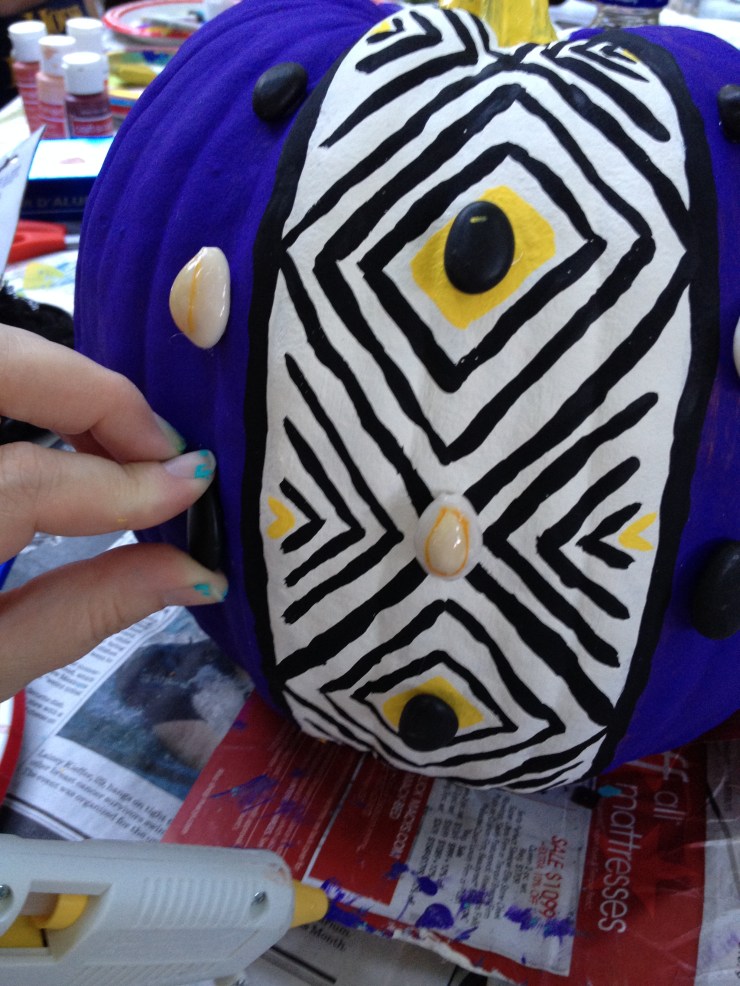 Step 5: After adding yellow accent color to design & the stem, use hot glue gun to attach river rocks and cowrie shells.